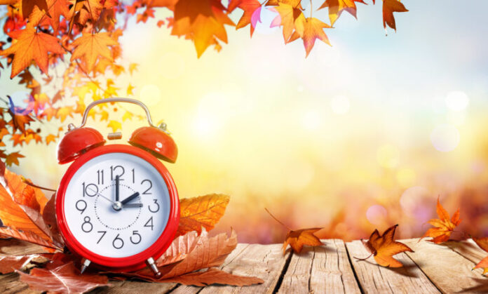 Daylight Savings Time Concept - Clock And Leaves On Wooden Table